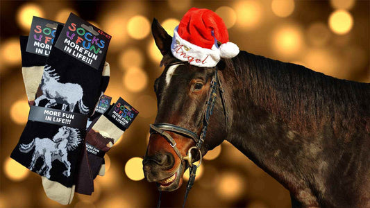 Le cheval a un bonnet de Père Noël sur la tête et sourit  en voyant les chevaux tricotés en motifs fantaisie sur les chaussettes amusantes qui sont une bonne idée cadeau à Noël.