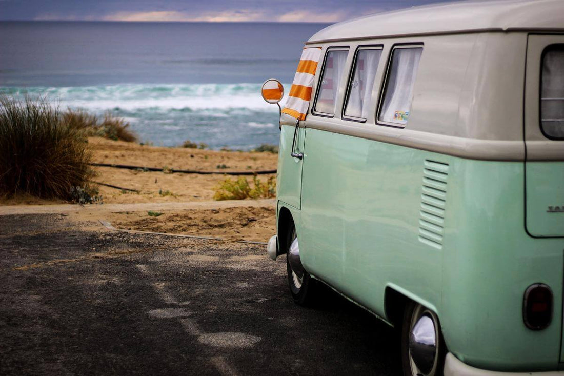 Camping car Combi Volkswagen vert garé devant le rivage avec la mer en face